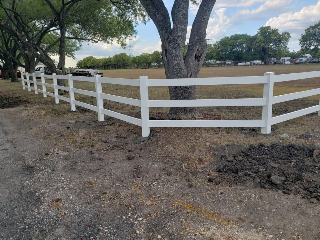 White vinyl rail fence across an open field