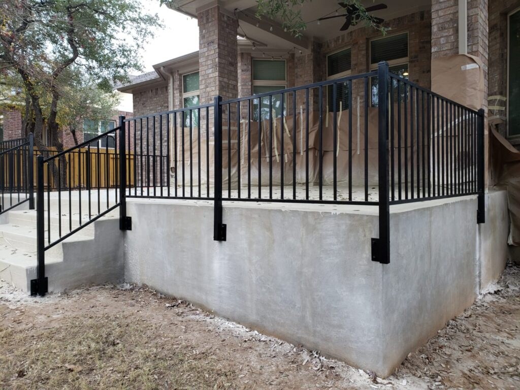 Black iron railing on a raised concrete porch